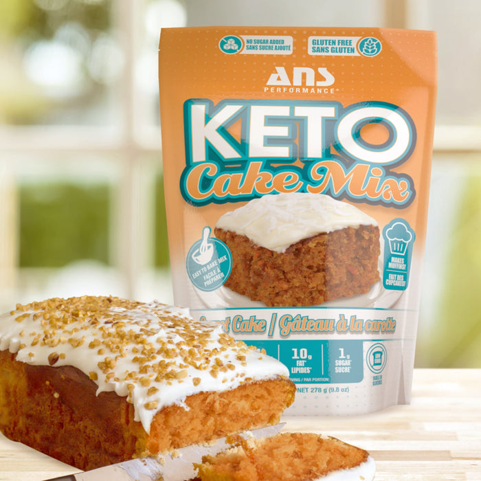 Baked carrot cake with frosting along with a packet of ANS Performance Keto Carrot Cake Mix.
