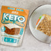 A picture of baked carrot cake with a packet of ANS Performance Keto Carrot Cake Mix packet alongside.