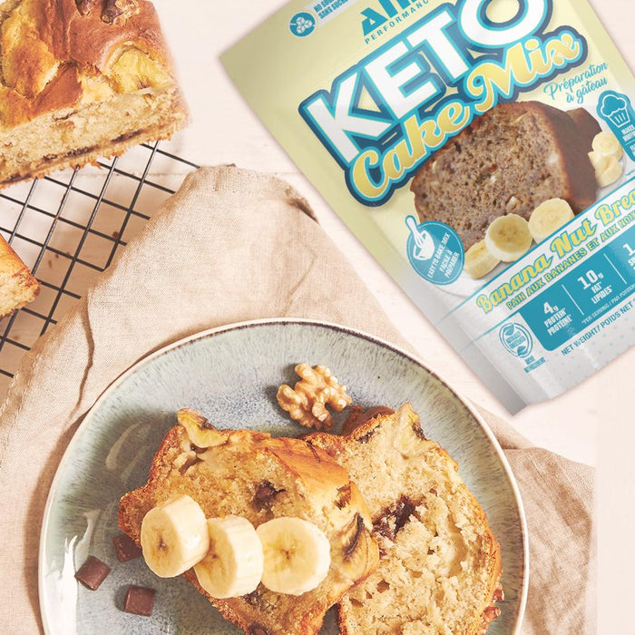 A picture of baked banana bread with a packet of A packet of ANS Performance Keto Banana Nut Bread Cake Mix in the background.